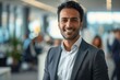 © btiger - Portrait of Successful Asian Indian Businessman Boss in Modern Office with Blurred Team in Background