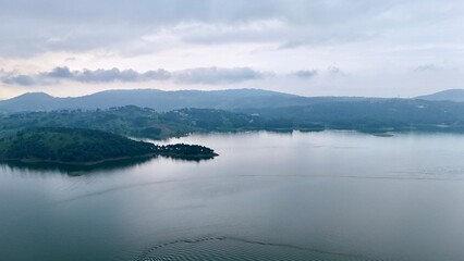 lake serene blue water with misty mountains aerial image is taken at umiam lake shillong meghalaya india. it is showing the breathtaking beauty of nature.
