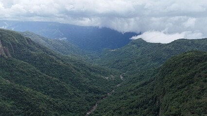 Lush green valley between mountains surrounded with clouds