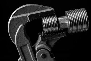 adjustable gas wrench on black background. Black and white photograph of a working tool