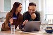 © Drazen - Happy couple banking online while using credit card and laptop at home.