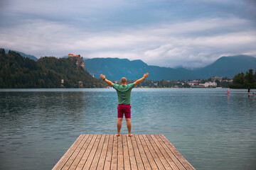 Man standing on wooden deck, pier at Bled lake, Slovenia