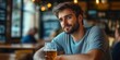 © Irina Ukrainets - A young man enjoys a refreshing drink in a cozy pub setting.