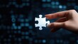 © starush - A hand holds a puzzle piece against a blurred digital background, symbolizing problem-solving, AI