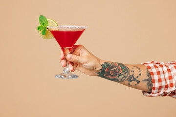 Close up cropped female barista bartender barman holding in hand glass of alcohol cocktail isolated on pastel plain light beige wall background studio. Pub bar concept. Copy space advertising mock up.