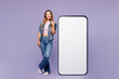 © ViDi Studio - Full body young woman wear denim jacket violet top casual clothes point index finger on big huge blank screen mobile cell phone smartphone with area isolated on plain pastel light purple background.