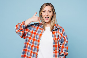 Wall Mural - Young shocked surprised woman wear red shirt t-shirt casual clothes doing phone gesture like says call me back isolated on plain pastel light blue cyan background studio portrait. Lifestyle concept.