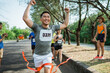 © Odua Images - asian male runner crossing finish line celebrating victory with hands up gesture