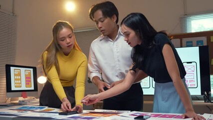 Wall Mural - team of ui designers working late in the office, reviewing and discussing the design of a mobile app