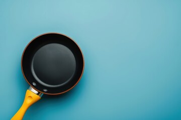 Non-stick frying pan with yellow handle on a blue background