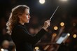© Larisa - Female conductor leading orchestra with precision and focus.