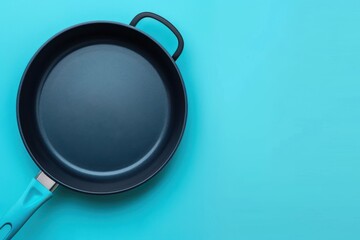 A blue frying pan on a turquoise background ready for cooking