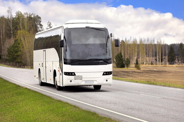 Wall Mural - white coach bus transports passengers along highway on a beautiful day of spring.