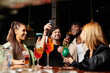 © LIGHTFIELD STUDIOS - A group of diverse colleagues shares laughter and cocktails at a trendy corporate gathering.