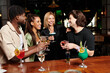 © LIGHTFIELD STUDIOS - A group of young professionals celebrates together, sharing drinks and smiles at a corporate event.