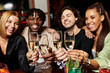 © LIGHTFIELD STUDIOS - Young colleagues joyfully raise their glasses in celebration at a lively corporate event.