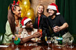 © LIGHTFIELD STUDIOS - Young professionals enjoy drinks and cheerful moments at a vibrant corporate holiday gathering.