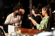 © LIGHTFIELD STUDIOS - Diverse professionals enjoying drinks and laughter at a fun corporate party with friends.