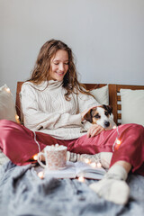 Wall Mural - Young woman with dog drinking warm coffee at home