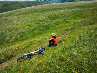 Canvas Print - Aerial view of woman riding mountain bike on flowering grassland mountain