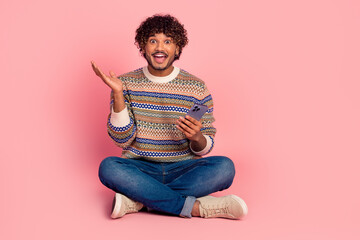 Canvas Print - Full size photo of nice young man sit floor smart phone wear pullover isolated on pink color background