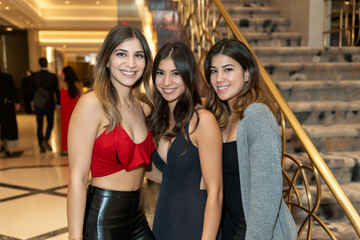 Three young gorgeous female students in sexy attire pose together at their prom, ready for an unforgettable night of partying.