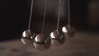 © KYR - Close-up of a silver Newton's cradle on a simple background, representing the physics of energy transfer and the balance