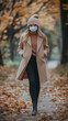 © AIRina - Woman in coat and face mask walking through autumn park during pandemic