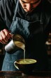 © Artem Zatsepilin - professional asian male barista adding whipped milk from small jug to cup of freshly made matcha. traditional tea ceremony. process of making healthy japanese beverage with natural ingredients