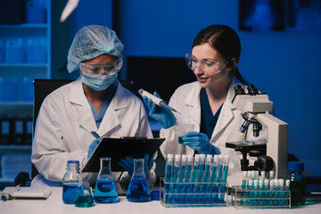 Wall Mural - team of biochemical research scientists working with a microscope for vaccine development