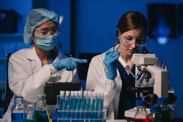 Wall Mural - team of biochemical research scientists working with a microscope for vaccine development