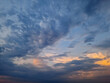 © airlifting - A vast sky view with dynamic clouds formation, hues of blue and subtle orange at the horizon, suggesting either sunrise or sunset. The interplay of light and cloudscape creates a serene atmosphere