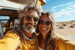 © k - Happy couple taking a selfie while traveling in New Mexico desert, wearing sunglasses and yellow sweatshirt, vintage camper van in background