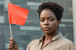 © Alexandra - Young Afro-American woman is holding a red warning flag and making a serious facial expression,   representing unhealthy relationship