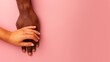 © Shutter2U - Two hands, one black and one white, intertwined on a pink background.