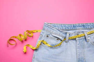 Poster - Jeans and measuring tape on pink background, top view