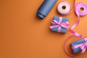 Canvas Print - Beautiful gift boxes with pink bows, ribbons and roll of wrapping paper on orange background, flat lay. Space for text