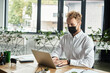 © LIGHTFIELD STUDIOS - A dedicated redhead businessman in a white shirt focuses on his project while seated at a stylish office desk.