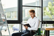 © LIGHTFIELD STUDIOS - A redhead in a white shirt diligently writes in a notebook, concentrating on his project in a contemporary workspace.
