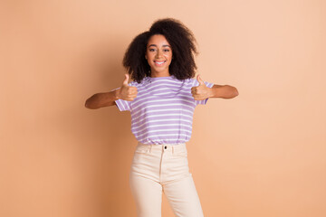 Canvas Print - Portrait of pretty young girl show thumb up wear striped t-shirt isolated on beige color background