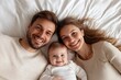 © Atlas Studio - Happy Family Laying on a Bed, Smiling Together With Their Baby in a Cozy Indoor Setting During the Daytime