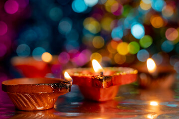 Diwali celebration background with glowing clay lamps and colorful lights.