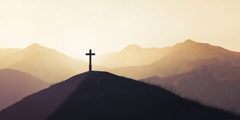 Wall Mural - Christian cross standing on a hilltop at sunset with mountains in the background