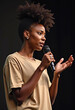 © PREM - A confident African American woman delivers a speech, holding a microphone and using her hand to express herself