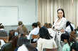 © EduLife Photos - A teacher carefully monitors students taking an exam in a classroom, ensuring focus and discipline during academic assessment.
