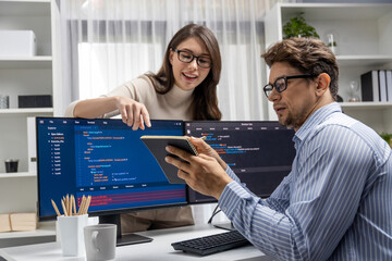 Wall Mural - woman colleague standing opposite to man programmer working on desk to discuss coding website softwa