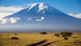 Majestic Kilimanjaro rises above the African savannah under a clear blue sky with grazing wildlife in the foreground
