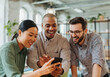 © Running opossum - Three business people laughing together while watching something funny on a smartphone in a modern office