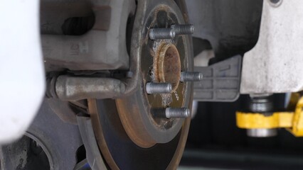 Close-up view of car wheel hub and brake disc assembly in auto repair shop, mechanical maintenance and repair.