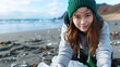 © Dmitriy - asian girl volunteer to clean plastic waste from a beautiful beach, emphasizing community action for ocean health
